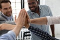 Happy motivated young multiethnic teammates uniting palms in high five