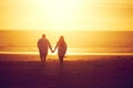 Together through sunsets and sunrises. Rearview shot of an affectionate mature couple walking hand in hand on the beach. Royalty Free Stock Photo