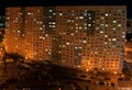 Panoramic view of a residential apartment building with many glowing windows late summer evening.