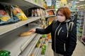 Red-haired girl in a medical mask chooses products in a supermarket.