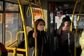 Togliatti, Samara region, Russia - March 27, 2020: A young red-haired girl in a medical mask rides to work in a city bus.