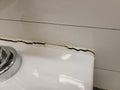 toilet in bathroom with crack in the wall or caulk