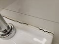 toilet in bathroom with crack in the wall or caulk