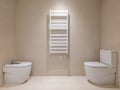 Toilet, bidet and heating radiator in a modern bathroom with beige tiles. Royalty Free Stock Photo