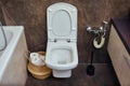 Toilet bowl with a hygienic shower next to the bath and a nightstand under the sink. Toilet paper basket and black marble tiles
