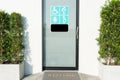 Toilet door with sign of disabled people, elderly, pregnant woman, and baby for their with welcome doormat and plant by the side. Royalty Free Stock Photo