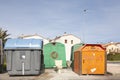 A toilet with its cistern among the garbage and recycling containers for organic waste, glass and vegetable oils in Plasencia