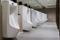 The toilet of man with Row of modern white ceramic urinals in public toilet or restaurant or hotel or shopping mall, interior