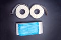 Toilet paper rolls are laid out in the form of an emoticon with a blue medical face mask. on a black background. virus outbreak