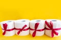 toilet paper rolls wrapped in gift bow. Bright yellow background. Copy space for the text.