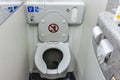 The toilet seat with the lid open at a aircraft lavatory. With a tissue dispenser and flush button above