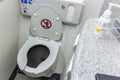 The toilet seat with the lid open at a aircraft lavatory. With a tissue dispenser and flush button above