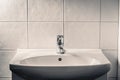 Toilet sink. Bathroom faucet, water tap and WC basin. Dramatic moody light with dark shadows. Public restroom. Royalty Free Stock Photo