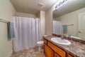 Toilet and vanity area inside bathroom with tiled floor and white shower curtain