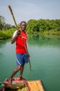 Tokeh Beach, Sierra Leone - January 06, 2014: Unidentified African man pushing simple raft on mangrove river with stick