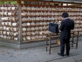 TOKYO, JAPAN - APRIL, 10, 2018: a man writes on a votive tablet at meiji shrine in tokyo, japan Royalty Free Stock Photo