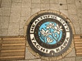 Manhole cover with illustraton in Tachikawa with the words `healthful city tachikawa`