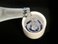 Pouring sake from sake bottle into small ceramic sake cup or small kiki-choko Royalty Free Stock Photo