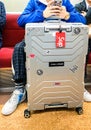Tokyo, Japan 10.02.2018 bright stylish aluminum suitcase with stickers next to fashionably dressed young man sitting in subway