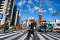Tokyo, Japan - December 25, 2018: People walking across the street in front of Tokyo Tower in beautiful cloudy blue sky Royalty Free Stock Photo