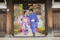 Tokyo, Japan- March 29,2019 an asian couple wearing traditional japanese clothes walking out from an old wood door frame Royalty Free Stock Photo