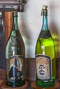 Old pressure cap glass bottles of japanese sake with a torn label.