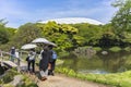 Japanese tourists holding sun umbrellas walking in the Koishikawa Korakuen Park.