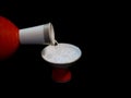 Pouring sake, liquor made from rice, from pottery choshi into a sakazuki or a cup on black background