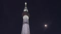 Worm`s-eye view video of the Tokyo Skytree tower beside a full moon.