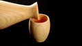 Pouring sake from wooden hinoki sake bottle, tokkuri, into wooden cup, Guinomi or Ochoko.