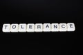 Tolerance text word title caption label cover backdrop background. Alphabet letter toy blocks on black reflective background. Whit