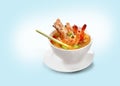 Tom Yam Kung Shrimp in a white bowl with Thai spices on a plate.