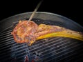 Tomahawk Steak cooking on charcoal grill with live coals - selective focus