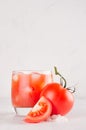 Tomato alcohol beverage in glass with ice cubes, tomato, salt and juicy slice on white wood table, copy space, vertical. Royalty Free Stock Photo
