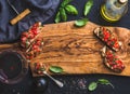 Tomato and basil bruschetta with glass of red wine, olive oil, salt, fresh herbs on wooden board over black background Royalty Free Stock Photo