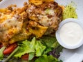 Tomato and beef lasagne with cheese layered between sheets of traditional Italian pasta served on a white plate