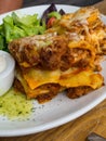 Tomato and beef lasagne with cheese layered between sheets of traditional Italian pasta served on a white plate on a restaurant or