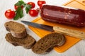 Tomato, parsley, slices of bread, smoked sausage, knife on cutting board on wooden table Royalty Free Stock Photo