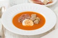 Tomato cold soup with egg and jamon on white dish
