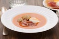 Tomato cold soup with egg and jamon on white dish