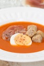 Tomato cold soup with egg and jamon on white dish