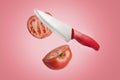 A tomato cut into two halves with a sharp knife. Levitation, healthy plant-based vegetarian food on a pink background Royalty Free Stock Photo