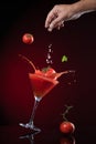 Tomato fall down in tomato juice with explosion and spashing of tomato juice on dark red background. Juice Levitation concept