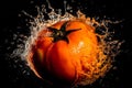 A tomato falls into clear water on a dark background