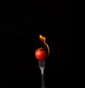 Tomato on fire with blue flames isolated on black background Royalty Free Stock Photo