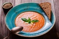 Tomato gazpacho soup with basil, feta cheese, ice and bread on dark wooden background, Spanish cuisine. Ingredients on table. Top