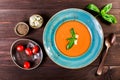 Tomato gazpacho soup with basil, feta cheese, ice and bread on dark wooden background, Spanish cuisine. Ingredients on table. Royalty Free Stock Photo