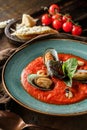 Tomato gazpacho soup with mussels, squid and cheese parmesan in plate over dark wooden background. Seafood, healthy food, close up