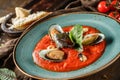 Tomato gazpacho soup with mussels, squid and cheese parmesan in plate over dark wooden background. Seafood, healthy food, close up