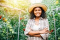 Amidst a tomato greenhouse a smiling woman farmer in checkered attire stands